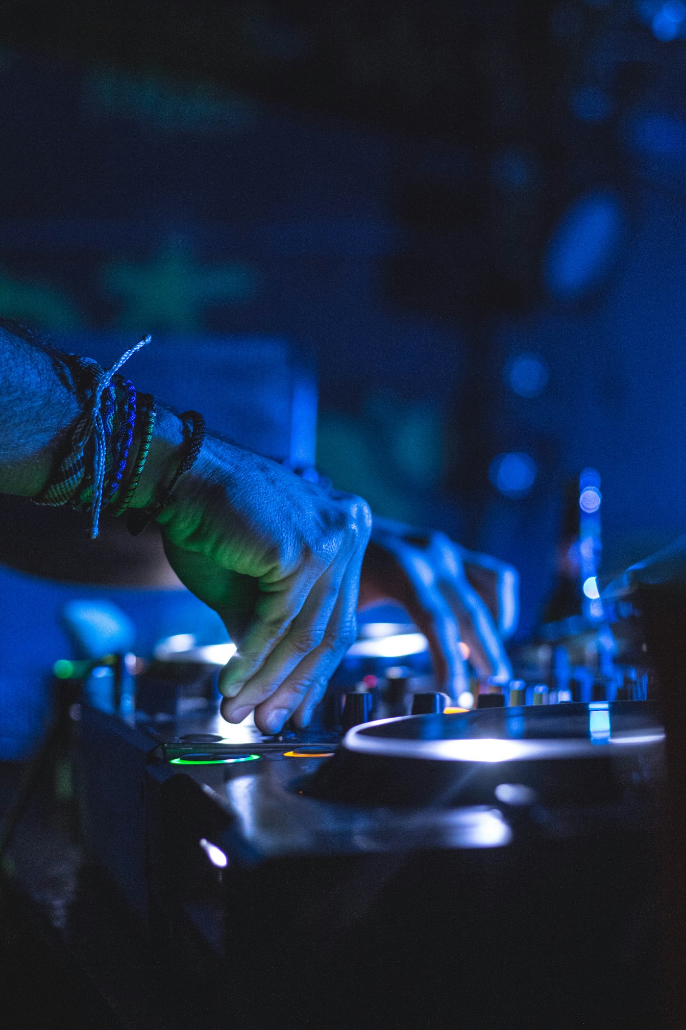 Handen op een DJ-controller in blauw neonlicht